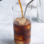 Pinterest Pin for how to make cold brew coffee show a photo of cold brew concentrate being poured into a glass of ice