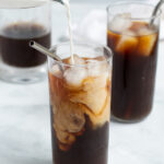 Pinterest Pin for cold brew coffee showing a picture of milk being poured in to cold brew making pretty swirls in the iced coffee