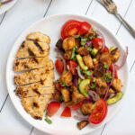 Pinterest Pin for Grilled Chicken Panzanella Salad showing a white plate with a grilled chicken breast and a pile of panzanella salad