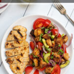 Pinterest Pin for Grilled Chicken Panzanella Salad showing a white plate with a grilled chicken breast and a pile of panzanella salad