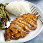 Pinterest Pin showing a grilled chicken breast sliced up on a plate net to grilled green beans