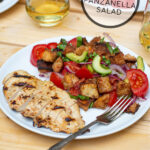 Pinterest Pin for Grilled Chicken Panzanella Salad showing a white plate with a grilled chicken breast and a pile of panzanella salad