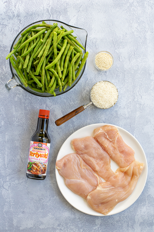flatly showing the five ingredients needed for the recipe, chicken breast, teriyaki sauce, white rice, green beans, and sesame seeds
