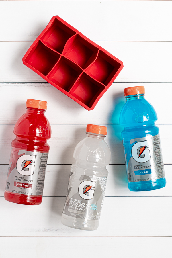 red, white, and blue gatorades laying next to a large ice cube tray, everything you need to make colorful ice cubes
