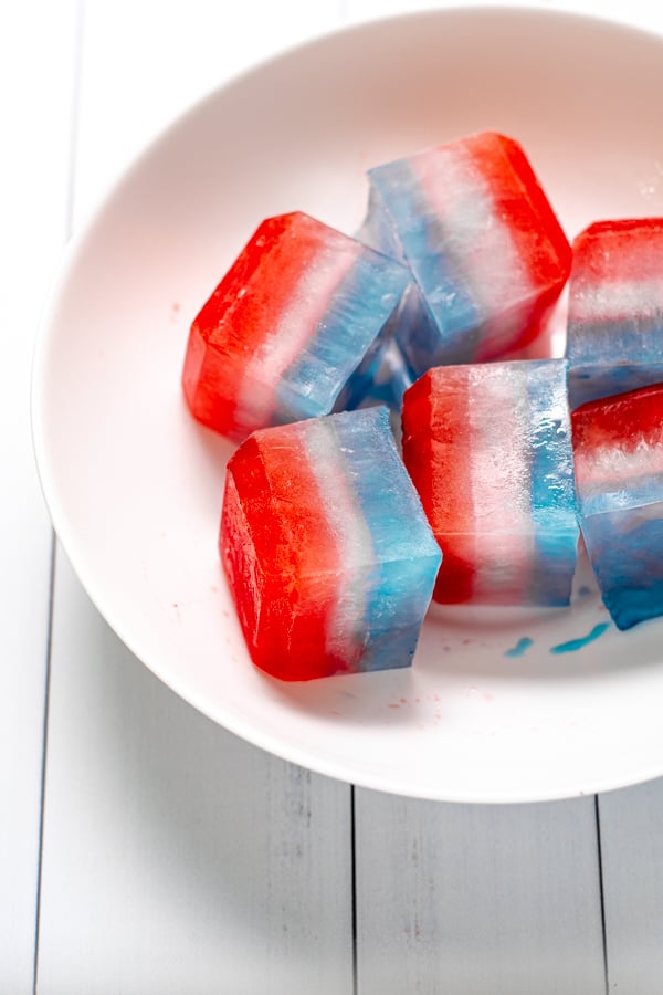 close up of layered red, white, and blue ice cubes in a large white bowl