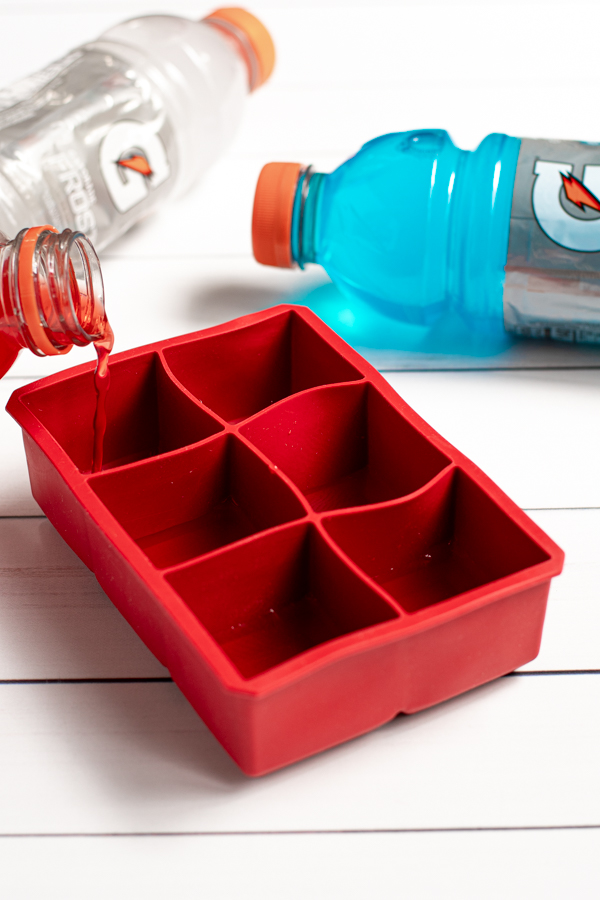 red gatorade being poured into a large red silicone ice cube tray