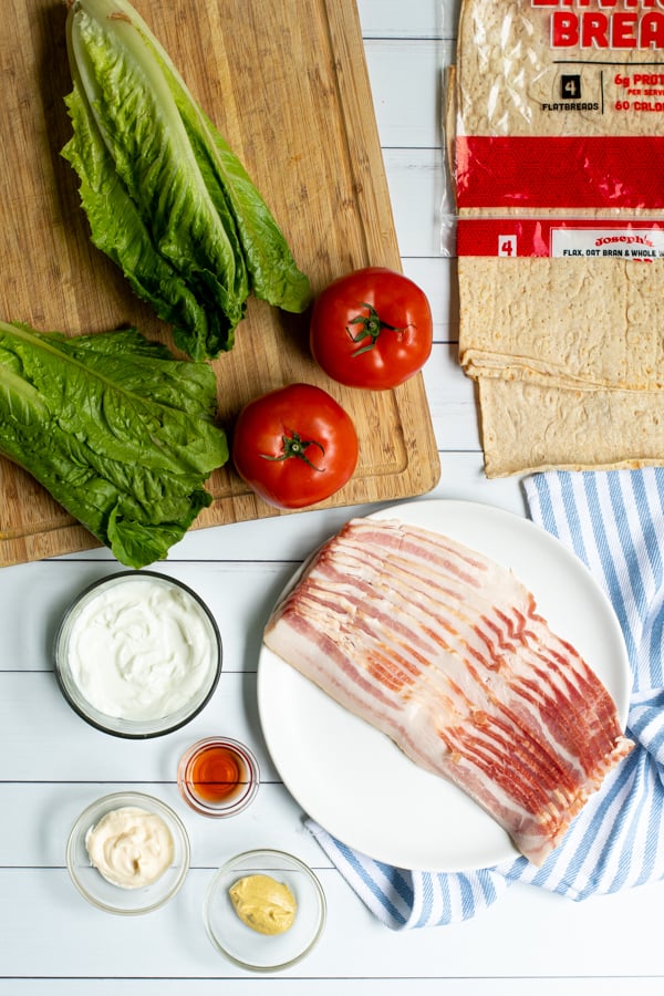 all of the ingredients needed to make BLT wraps lated out on plates and cutting boards