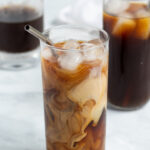 Pinterest Pin for How to make Cold Brew Coffee showing a glass of cold brew coffee swirled with freshly poured milk with ice and a straw