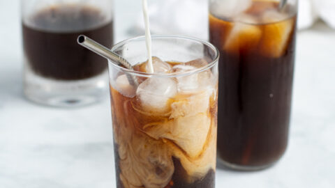 milk being poured into a glass of homemade cold brew coffee making milk and coffee swirls in the glass