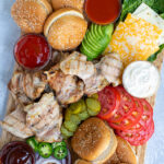 Pinterest Pin for Grilled Chicken Sandwich Board showing a large bamboo cutting board holing grilled chicken, sauces, and toppings