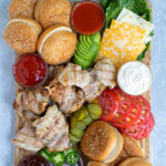 Pinterest Pin for Grilled Chicken Sandwich Board with an image of a board with grilled chicken, sauces, buns, and toppings