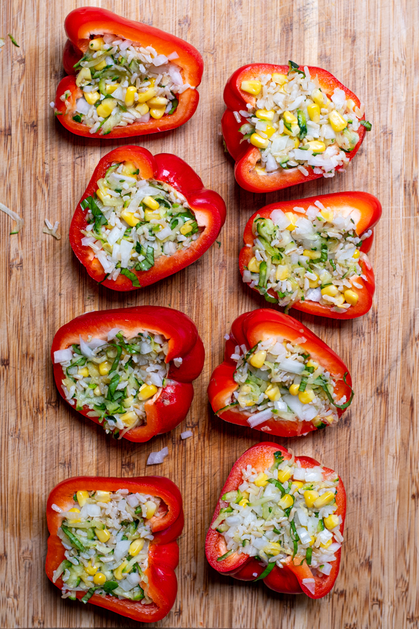 uncooked stuffed red bell peppers on a cutting board