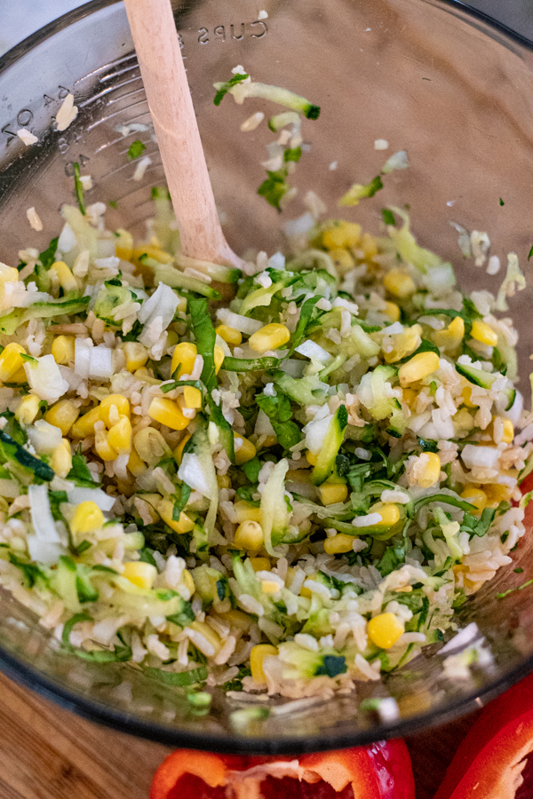 vegetable filling in a bowl for stuffed peppers featuring zucchini, corn, onions, rice, & herbs