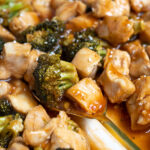 Pinterest Pin for Baked General Tso's Chicken showing a baking dish full of saucy chicken with a serving spoon