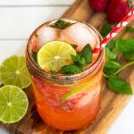 Pinterest Pin for Strawberry Mojito Mocktail showing a pink beverage in a glass with ice garnished with fresh mint and lime slices