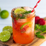 Pinterest Pin for Strawberry Mojito Mocktail showing a pink beverage. in a glass on a cutting board garnished with fresh mint and lime slices
