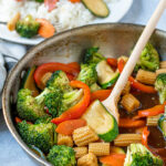 Pinterest Pin for Easy Veggie Stir Fry with a photo of colorful saucy veggies in a skillet with a wooden spoon