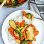 Pinterest Pin for Easy Veggie Stir Fry with a photo of vegetables on a bed of white rice with a forkful of veggies
