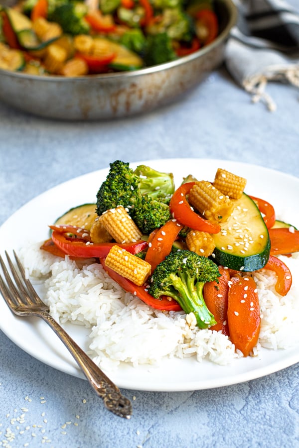 easy vegetables stir fry on a plate served with rice and garnished with sesame seeds
