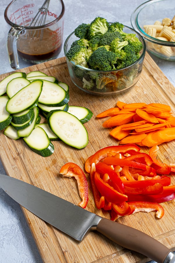 cut up vegetables on a wooden cutting board with a knife