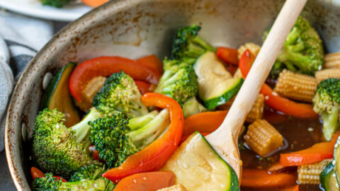 simple vegetable stir fry in a skillet with a wooden spoon