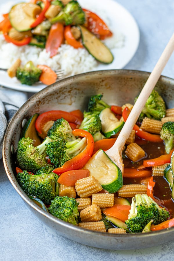 simple vegetable stir fry in a skillet with a wooden spoon