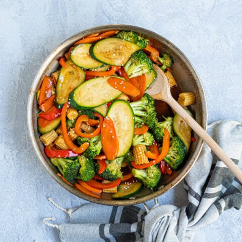 easy vegetable stir fry in a aluminum skillet with a wooden spoon
