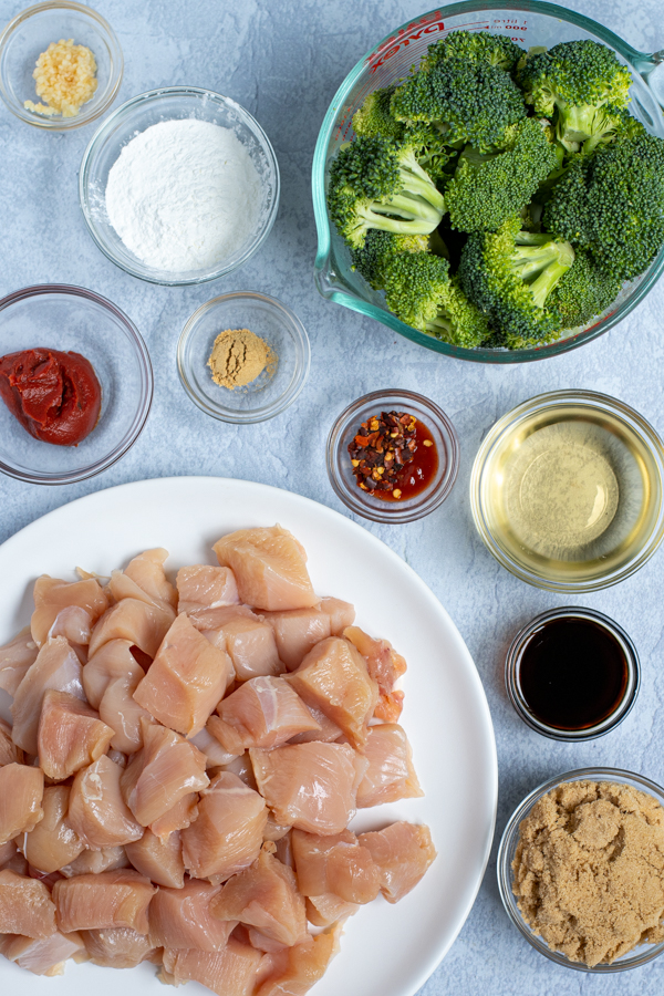 all of the ingredients needed to make healthy baked general tso chicken laid out including diced chicken and broccoli