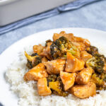Pinterest Pin for Baked General Tso's Chicken showing a plate with rice topped with a large scoop of saucy chicken and broccoli