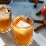Pinterest Pin with text overlay Apple Cider Bourbon Cocktail, image of whiskey glass full of bourbon cider garnished with cinnamon sticks and apples.