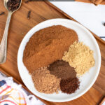 Pinterest Pin with text overlay Homemade Pumpkin Pie Spice includes a photo of a small white plate filled with 5 piles of spices used for the blend.
