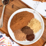Pinterest Pin with text overlay Homemade Pumpkin Pie Spice, photo of a small white plate with 5 little piles of spices on it for the recipe.
