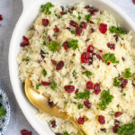Pinterest Pin with Text Overlay 'Rice Pilaf with Cranberries', image shows white dish with cranberry rice pilaf.