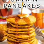 Pinterest Pin with Text overlay Homemade Pumpkin Pancakes showing a tall stack of pancakes on a white plate with maple syrup being poured on the top and dripping down the sides of the pancake.