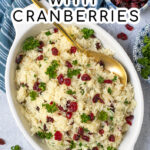 Pinterest Pin with Text Overlay 'Rice Pilaf with Cranberries', image shows a large oval serving dish filled with pilaf and topped with dried cranberries and parsley.