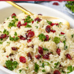 Pinterest Pin with Text Overlay 'Rice Pilaf with Cranberries', image shows serving dish filled with rice topped with dried cranberries and parsley.