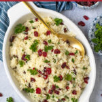 Pinterest Pin with Text Overlay 'Rice Pilaf with Cranberries', image shows serving dish with cranberries and parsley on top of rice.