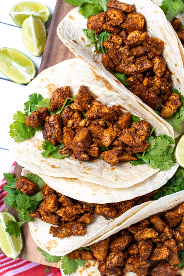 The best chicken taco filling inside a tortilla next to cilantro.