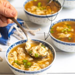Pinterest Pin with text over lay 'Homemade Egg Drop Soup' with image of small bowl full of soup with a spoon, and topped with green onions.