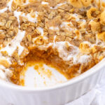 Pinterest Pin with Text: Sweet Potato Casserole with Marshmallow & Oat Streusel, showing a casserole dish with a scoop of sweet potatoes taken out.