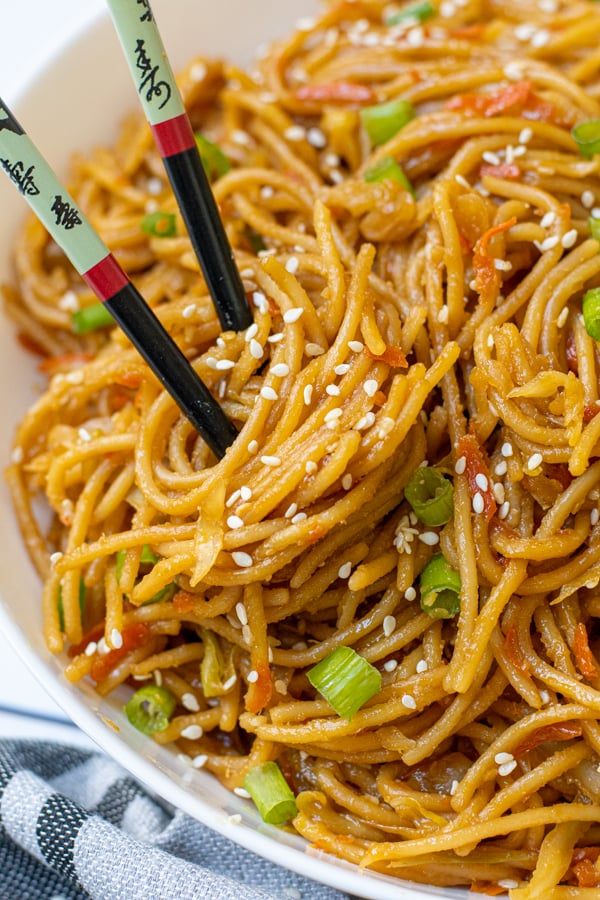 A pair of black chopsticks twisted into homemade teriyaki noodles.