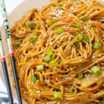 Pinterest Pin with text, One-Pot Teriyaki Noodles. Image of a while bowl of saucy noodles with chopsticks and topped with sesame seeds and green onions.