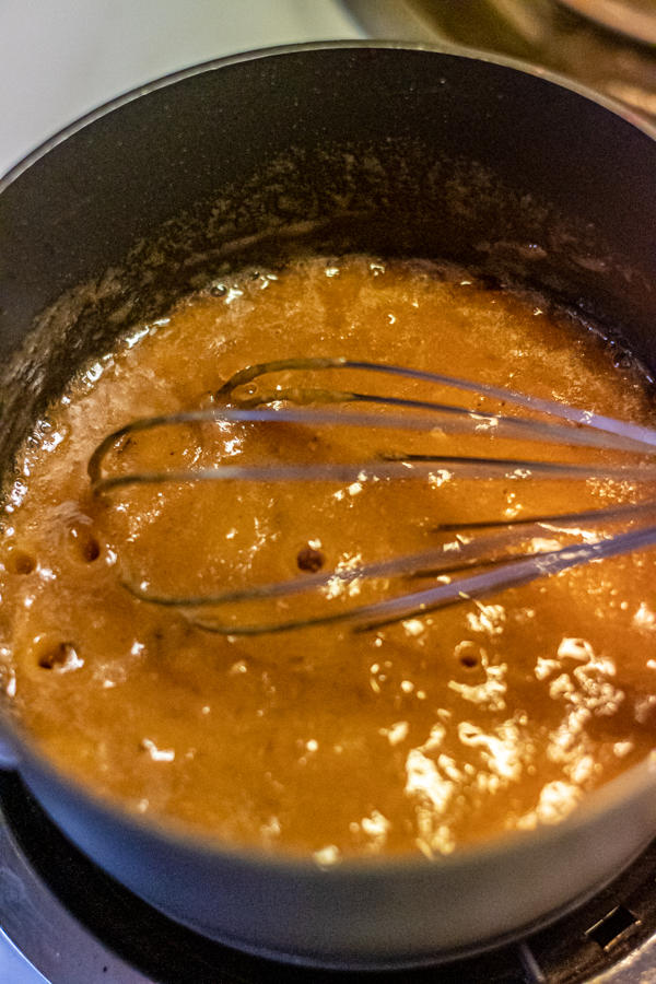 Saucepan with bubbling brown roux from turkey drippings with a whisk.
