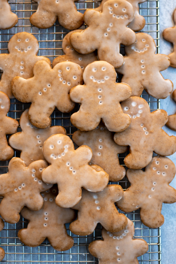 A pile of glazed gingerbread men on a wire cooling rack.