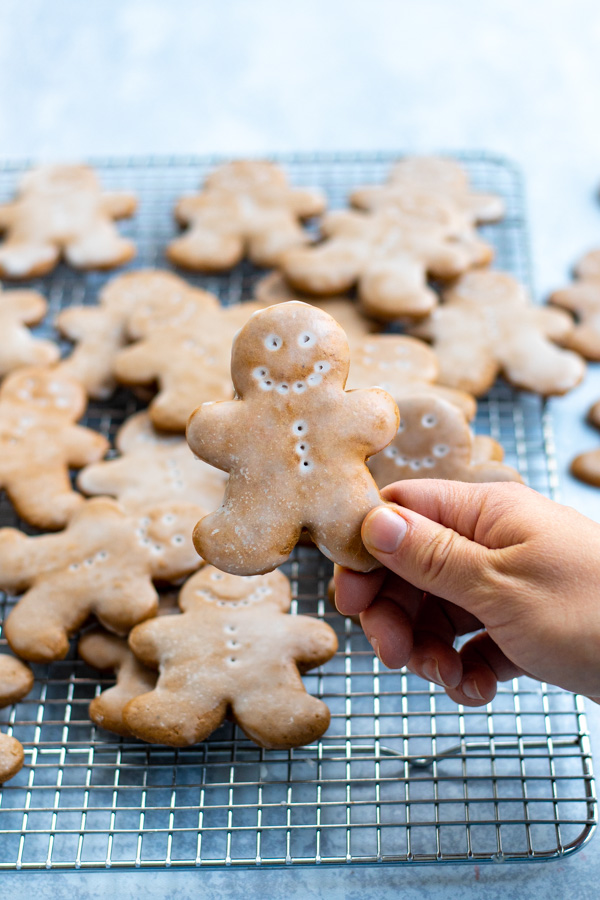 A hand holding a single glazed gingerbread man.
