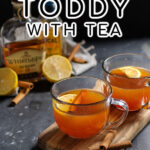 Pinterest Pin with text overlay 'Hot Toddy with Tea'. Image of a clear mug filled with hot toddy and garnished with a cinnamon stick and lemon slice.