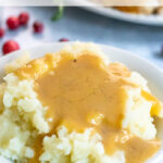 Pinterest Pin with text, Turkey Gravy Made From Pan Drippings. With a huge bowl of mashed potatoes covered in a large pool of turkey gravy.