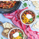 Pinterest Pin with text overlay, Crockpot Vegetarian Chili. Image of two bowls and a crockpot full of chili on a table the bowls are garnished with sour cream, cheese, and cilantro.