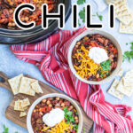 Pinterest Pin with text overlay, Three Bean Crockpot Chili. Image of two bowls and a crockpot of chili on a table with spoons, saltines, and a red kitchen towel.