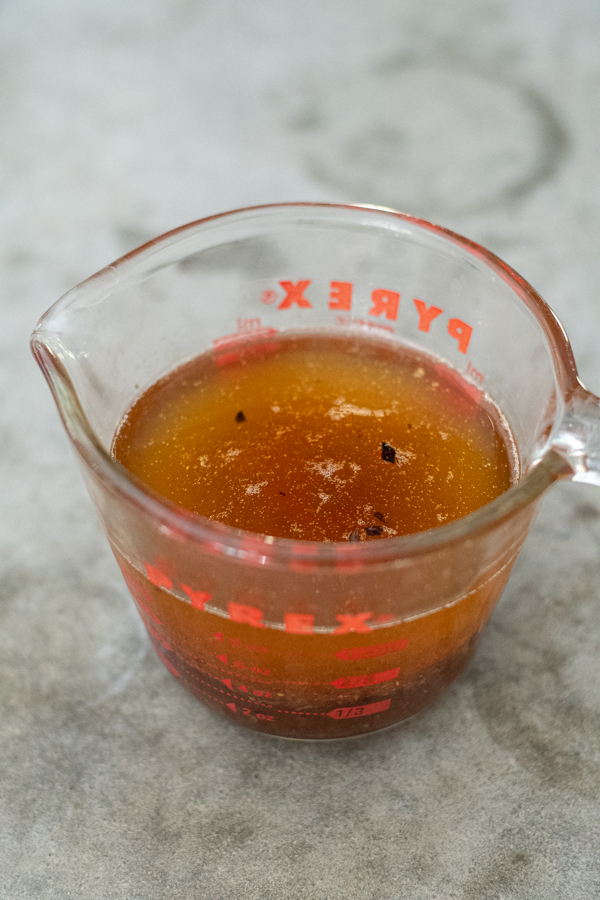 A cup of turkey drippings in a glass measuring cup.